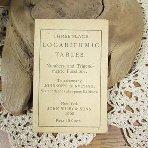 May include: A vintage, off-white paper booklet titled Three-Place Logarithmic Tables, Numbers and Trigonometric Functions, to accompany Johnson's Surveying, Sixteenth and subsequent Editions, New York, John Wiley & Sons, 1900, Price 15 Cents.