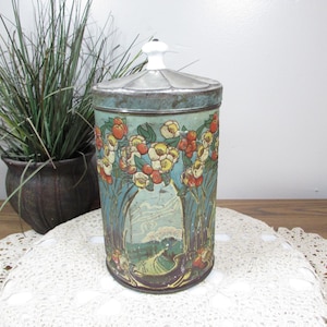 May include: Vintage cylindrical tin with a lid, featuring a floral design in shades of red, yellow, and white against a teal background. The lid has a white knob. The tin is approximately 7 inches tall, perfect for storage.