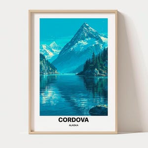 Può includere: Una stampa artistica incorniciata raffigurante un paesaggio di Cordova, in Alaska, con montagne innevate, un lago blu profondo e alberi sempreverdi. Il testo CORDOVA ALASKA è stampato in nero sul bordo bianco all'interno della cornice in legno chiaro.