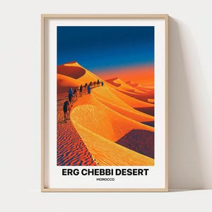 May include: A framed vertical art print featuring a desert landscape with orange sand dunes and a caravan of camels walking along a ridge. The sky transitions from deep blue to orange. The text reads ERG CHEBBI DESERT MOROCCO at the bottom.