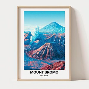 Op de afbeelding: Een ingelijste kunstdruk met een landschapsillustratie van de Mount Bromo in Indonesië. De afbeelding toont een vulkanische krater met een pluim witte rook, blauwe en roze bergkammen en een heldere lucht. De tekst MOUNT BROMO INDONESIA staat eronder gedrukt.