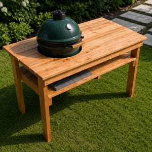 May include: A rectangular light brown wooden table with a slatted surface and a lower shelf. A dark green, dome-shaped ceramic grill with a silver temperature gauge and a black handle is set into a circular cutout on the top of the wooden table.