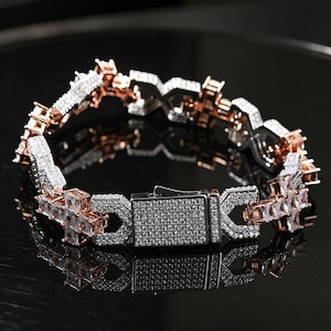 May include: A rose gold and silver bracelet with a rectangular clasp. The bracelet is encrusted with small, sparkling stones. The links alternate between rose gold and silver, creating a striking contrast. The bracelet is designed with a geometric pattern.
