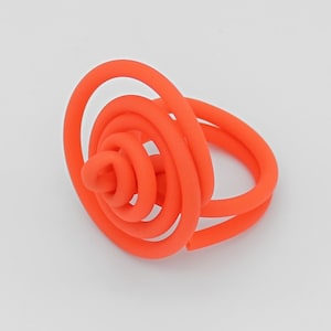 May include: A bright orange ring made of multiple intertwined coils of plastic. The coils are arranged in a spiral pattern, creating a unique and modern design.