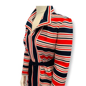 May include: A striped dress with a long sleeve, a collar, and a belt. The dress is red, white, and navy blue.