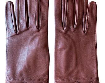 May include: A pair of brown leather gloves featuring a smooth finish and a decorative diamond-shaped stitched pattern along the wrist area. The gloves have five fingers each and are displayed side by side against a plain white background.