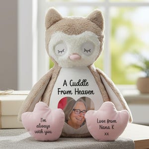 May include: A plush owl toy with tan and cream fur, featuring closed eyes and a pink nose. The white belly displays the text A Cuddle From Heaven above a heart-shaped photo of a person. The pink feet are printed with I'm always with you and Love from Nana K XX.