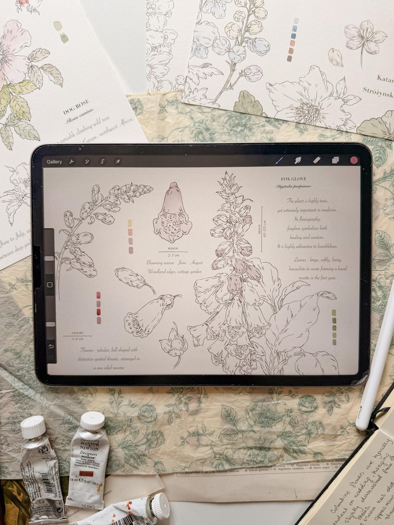 May include: A digital tablet displaying a botanical illustration of a foxglove plant with line drawings, color swatches, and text. The screen shows the plant's name, scientific name, blooming season, and descriptive notes in English.