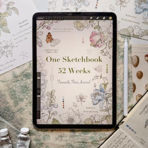 May include: A digital tablet displaying a cover titled One Sketchbook 52 Weeks Fauna & Flora Journal by Katarzyna Str&oacute;żyńska-Goraj, featuring botanical and insect illustrations in soft colors, accompanied by a white stylus and paint tubes.