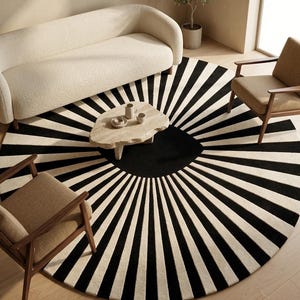 May include: A large circular area rug featuring a bold sunburst pattern with alternating black and off-white radiating stripes. The design centers on a solid black circle, with the stripes extending outward to the edge of the round rug.