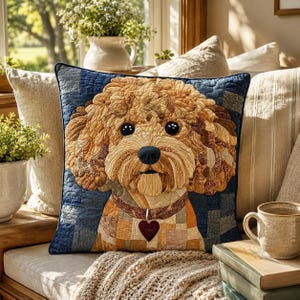May include: A square throw pillow featuring a quilted applique of a curly-haired golden dog. The dog has dark eyes, a black nose, and a brown collar with a heart-shaped charm. The background is a blue patchwork design with quilted textures.