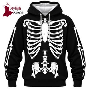 Könnte beinhalten: Ein schwarzer Kapuzenpullover mit langen Ärmeln und einem weißen Grafikdruck eines menschlichen Brustkorbs, der Wirbelsäule und des Beckens auf der Vorderseite. Der Hoodie hat weiße Kordelzüge und ein weißes Innenfutter in der Kapuze.