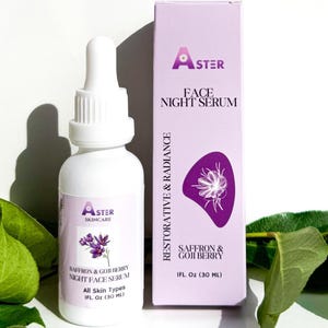 May include: A white bottle of Aster Skincare Face Night Serum with a dropper, next to a matching box. The box and label feature the text "Saffron & Goji Berry" and a purple floral design. Green leaves are in the foreground.