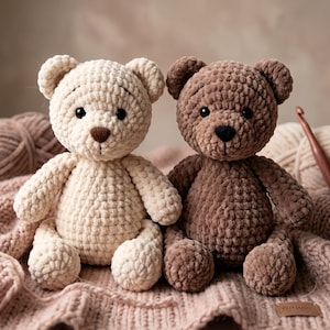 Può includere: Due orsacchiotti di peluche realizzati in filato morbido e spesso. Un orso è color crema con il naso marrone, l'altro è marrone scuro con il naso nero. Entrambi hanno orecchie rotonde, piccoli occhi neri e una bocca cucita, seduti in posizione.
