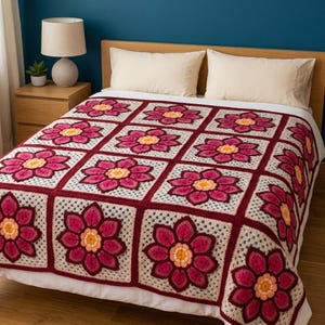 May include: A handmade crochet blanket featuring a repeating pattern of large, multi-layered floral motifs. Each square displays a central yellow and orange flower surrounded by deep magenta petals, framed by a light cream-colored border.