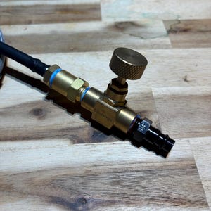 May include: A brass and black valve assembly with a textured knob and blue accents. A black hose is connected to the valve. The valve has the text "Lidorango" printed on it. The valve has a 1/4" fitting.