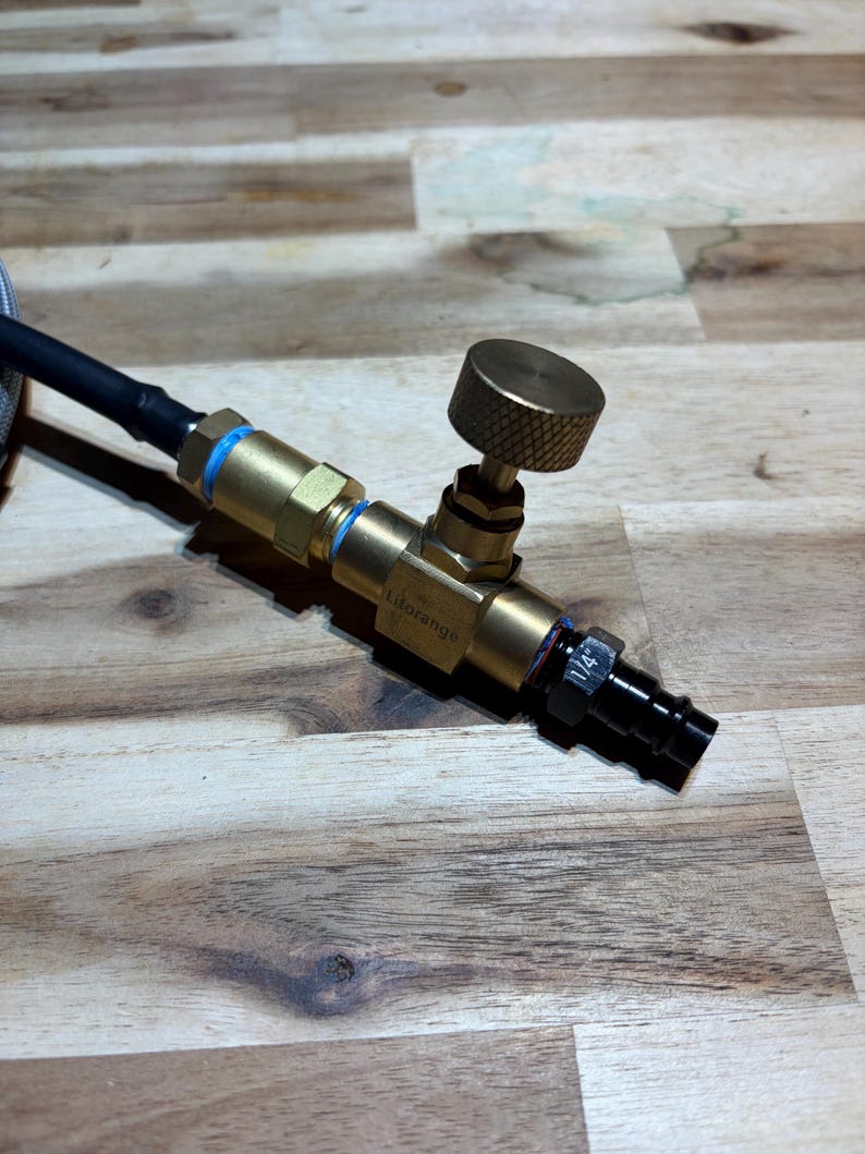 May include: A brass and black valve assembly with a textured knob and blue accents. A black hose is connected to the valve. The valve has the text "Lidorango" printed on it. The valve has a 1/4" fitting.