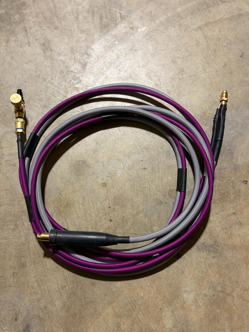May include: Coiled audio cable with purple and gray braided sheathing. The cable has gold-colored connectors and a black connector. The cable is designed for audio equipment.