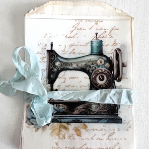 May include: A vintage-style sewing machine with intricate details, including floral patterns and a spool of thread. The machine is on a piece of paper with handwritten text, including the words "spirit" and "be in".