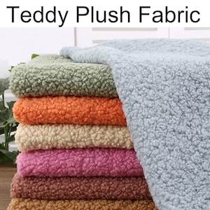 May include: A stack of teddy plush fabric in various colors, including green, orange, cream, pink, brown, and blue. The fabric has a soft, textured appearance. The words "Teddy Plush Fabric" are at the top of the image.