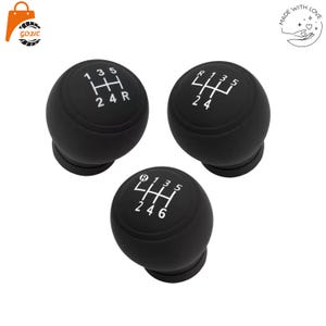 May include: Three black gear shift knobs with white markings. Each knob has a different gear pattern: 1, 3, 5, H, 2, 4, R; R, 1, 3, 5, H, 2, 4; and R, 1, 3, 5, H, 2, 4, 6. The knobs are round with a base.