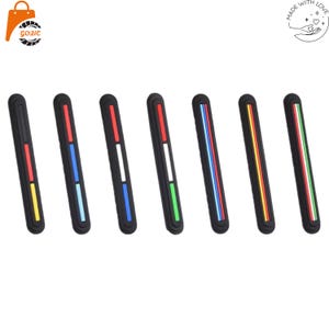 May include: Seven elongated black protective strips, each featuring a distinct vertical color pattern. The strips display various combinations of red, yellow, blue, light blue, white, and green accents set within a recessed center channel.