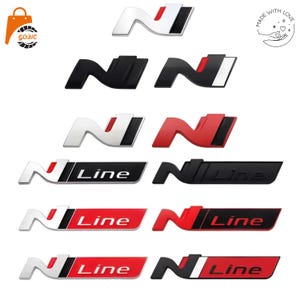 Könnte beinhalten: Eine Sammlung von Auto-Emblemen mit dem Buchstaben N und N Line-Logos in verschiedenen Farbkombinationen, darunter Chrom, Mattschwarz und Rot. Die Embleme sind in Reihen angeordnet und zeigen verschiedene Ausführungen und Stile für Fahrzeuglogos.