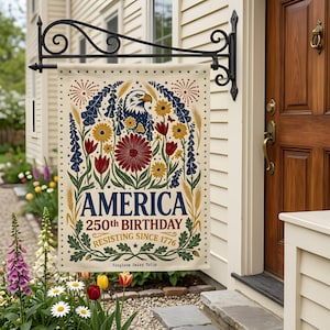 May include: A rectangular outdoor flag with a floral design and the text "AMERICA 250th BIRTHDAY RESISTING SINCE 1776". The flag features an eagle, flowers, and fireworks in red, blue, and yellow.