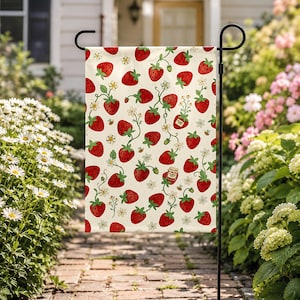 May include: A rectangular garden flag featuring a repeating pattern of red strawberries, green stems, white flowers, and small bees on a cream background. The design includes a small jar of strawberry jam with a red lid and a white label.