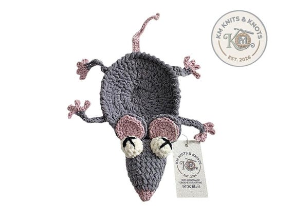 A hand-crocheted rat that looks gloriously squashed flat — equal parts gross and adorable as a mug coaster.