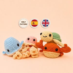 Puede incluir: Un conjunto de cuatro pequeñas criaturas marinas de ganchillo que incluye una ballena azul claro, una medusa rosa, una tortuga verde y un cangrejo naranja. Arriba, tres iconos circulares muestran el texto ONLY PATTERN y las banderas de España y el RU.