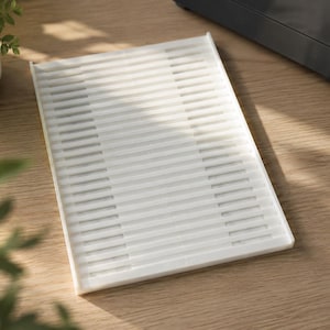 May include: A rectangular white plastic tray featuring a series of parallel horizontal slats across its surface. The tray has a raised edge along the top side and a flat, smooth border framing the slatted center section, designed for drainage.