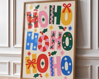 May include: A framed vertical wall art print featuring the text HO HO HO repeated in a colorful, festive design. The letters are decorated with patterns including red bows, green holly leaves, blue stars, pink wavy lines, and multi-colored string lights.