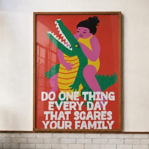 Puede incluir: Un cuadro rectangular enmarcado con fondo rojo que presenta una ilustraci&oacute;n gr&aacute;fica de una persona en traje de ba&ntilde;o amarillo abrazando a un cocodrilo verde. El texto dice: DO ONE THING EVERY DAY THAT SCARES YOUR FAMILY en letras blancas negritas.