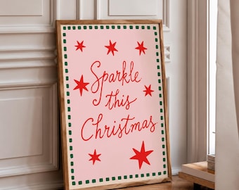 May include: A rectangular wooden frame containing a light pink poster with the red text Sparkle this Christmas. The poster features a border of small green squares and several red star illustrations of varying sizes scattered around the text.