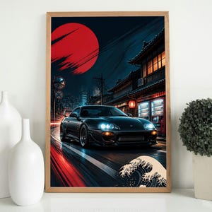 May include: A framed wall art print featuring a black sports car driving on a city street at night. The scene includes a large red sun, traditional architecture, glowing vending machines, and a stylized wave graphic in the bottom corner.