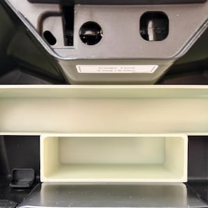 May include: An interior view of a black compartment with a light beige plastic tray and a smaller rectangular compartment below it. The tray is open and has a rectangular shape. The overall theme is storage.