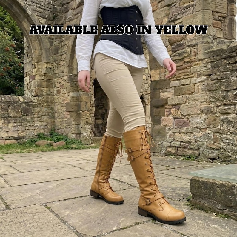 May include: Tan knee-high boots featuring a lace-up front, side zippers, and two buckled straps at the ankle and calf. The boots are worn with beige pants, a white long-sleeved shirt, and a black corset. Text reads: AVAILABLE ALSO IN YELLOW.