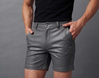 Op de afbeelding: Een grijze korte broek gemaakt van een glad, leerachtig materiaal. De broek heeft een gestructureerde tailleband met een enkele knoopsluiting, riemlussen en twee zijzakken. Het ontwerp is voorzien van een strakke zoomlijn.