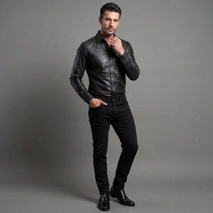 May include: A black leather shirt with long sleeves and a button-down design. The shirt is paired with black jeans and black dress shoes. The outfit is a classic, monochromatic ensemble.