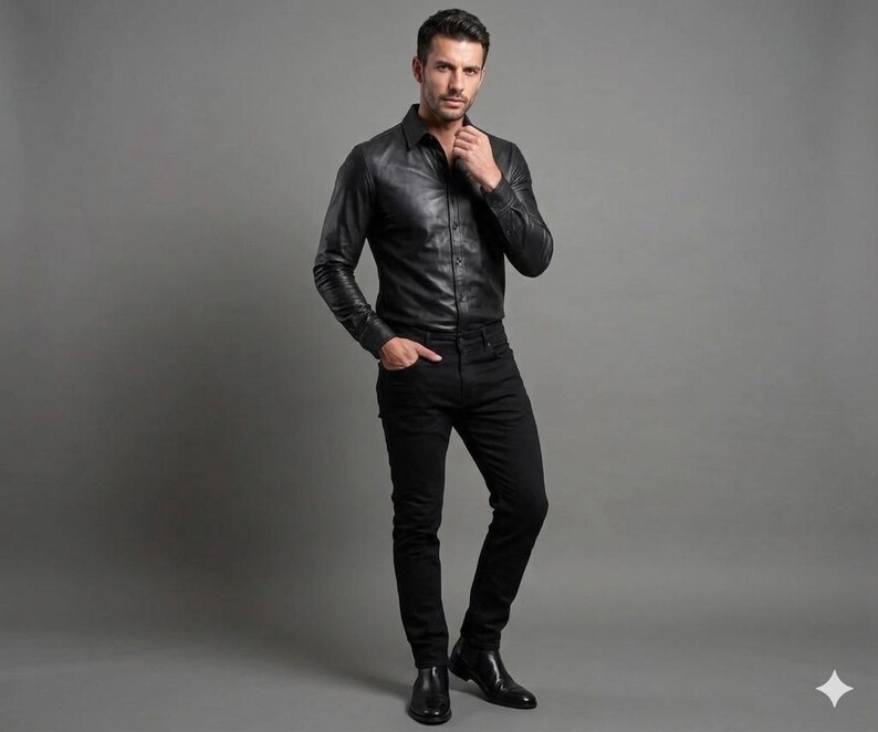 May include: A black leather shirt with long sleeves and a button-down design. The shirt is paired with black jeans and black dress shoes. The outfit is a classic, monochromatic ensemble.