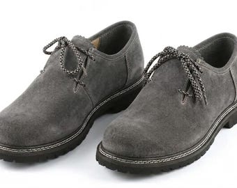 Op de afbeelding: Een paar grijze suède veterschoenen met een ronde neus, een laag model en dikke zwarte profielzolen. De schoenen zijn voorzien van gespikkelde grijs-zwarte veters en hebben zichtbare witte stiksels langs de rand van de zool.