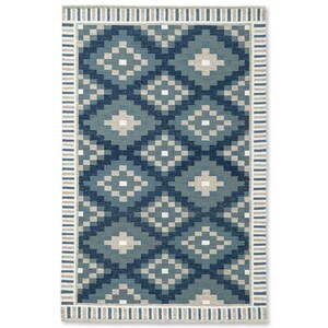 May include: Rectangular area rug with a geometric pattern in shades of blue and beige. The rug features a repeating diamond design in varying shades of blue, with beige accents. A striped border in beige and white frames the patterned center.