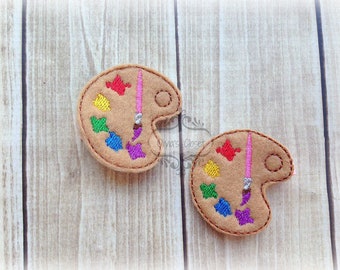 May include: Two felt paint palettes with a paintbrush and colorful paint swatches. The palettes are brown with a light brown outline. The paint swatches are red, orange, yellow, green, blue, purple, and pink.
