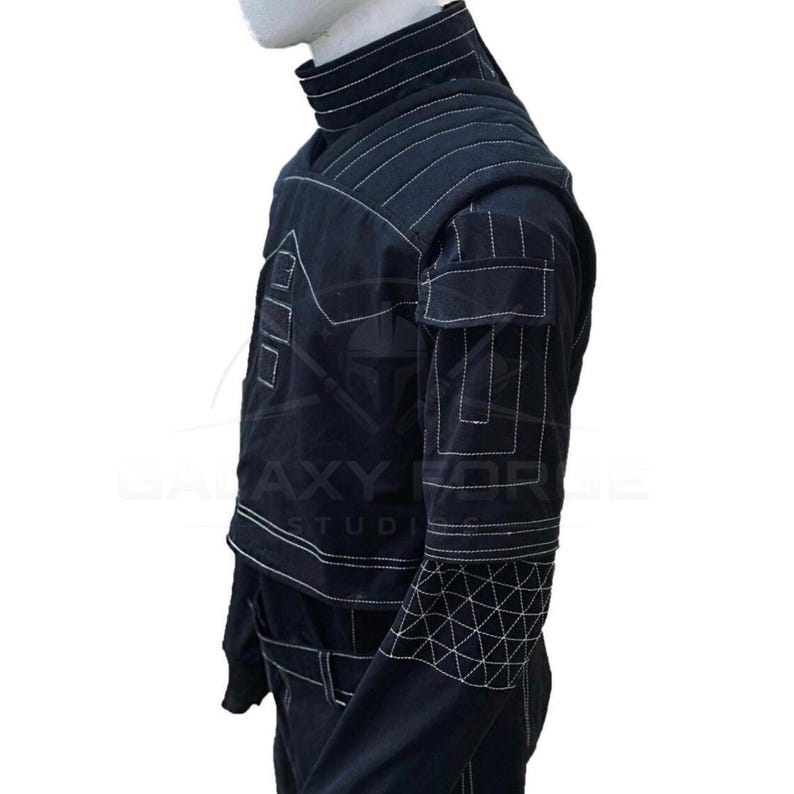 May include: Black jacket with white stitching details. Features include a high collar, multiple pockets, and geometric patterns on the sleeves. The jacket has a tailored fit and a unique design.