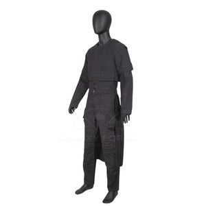 Op de afbeelding: Een zwarte jumpsuit op een etalagepop, voorzien van een gestructureerd lijfje met verticale stiksels, lange mouwen en een gelaagd rokpaneel. Het kledingstuk heeft meerdere zakken op de broekspijpen en een ronde halslijn in een effen zwarte kleur.