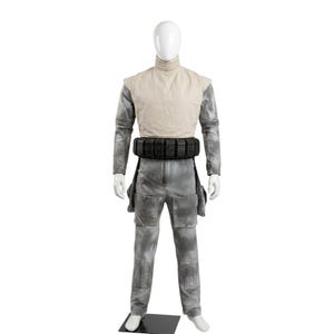 K&ouml;nnte beinhalten: Ein Ganzk&ouml;rperkost&uuml;m auf einer Schaufensterpuppe mit einer hellbeigen, &auml;rmellosen Weste mit hohem Kragen &uuml;ber einem grauen Langarm-Overall. Das Outfit umfasst einen schwarzen G&uuml;rtel mit mehreren rechteckigen Taschen und gro&szlig;en Cargotaschen.