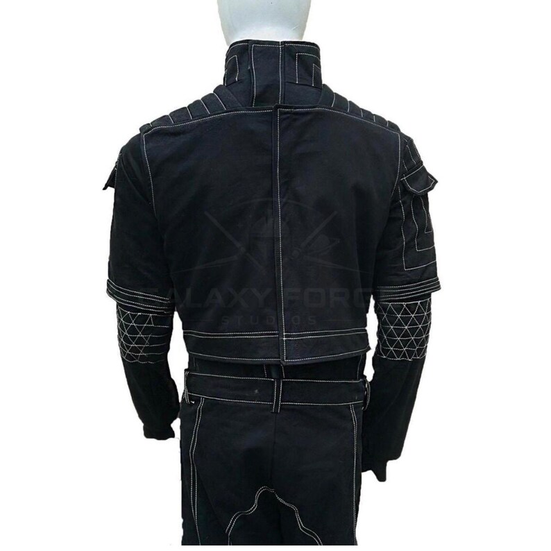 May include: Black jacket with white stitching details. Features include a high collar, multiple pockets, and geometric patterns on the sleeves. The jacket has a belt at the waist and is made of a durable material.