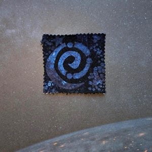 Peut inclure: Un patch de tissu carré bleu foncé avec un motif en spirale bleu clair. Le patch a un aspect texturé et un bord décoratif. L'arrière-plan montre un ciel étoilé et une vue de la Terre depuis l'espace.