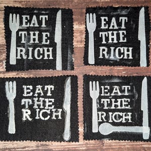Pode incluir: Quatro quadrados de tecido preto com o texto "EAT THE RICH" em branco, acompanhados por ilustrações brancas de um garfo, uma faca e uma colher. Os quadrados estão dispostos numa grelha 2x2.